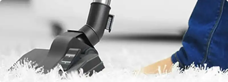 Close-up of a professional vacuuming a white carpet in Canton.